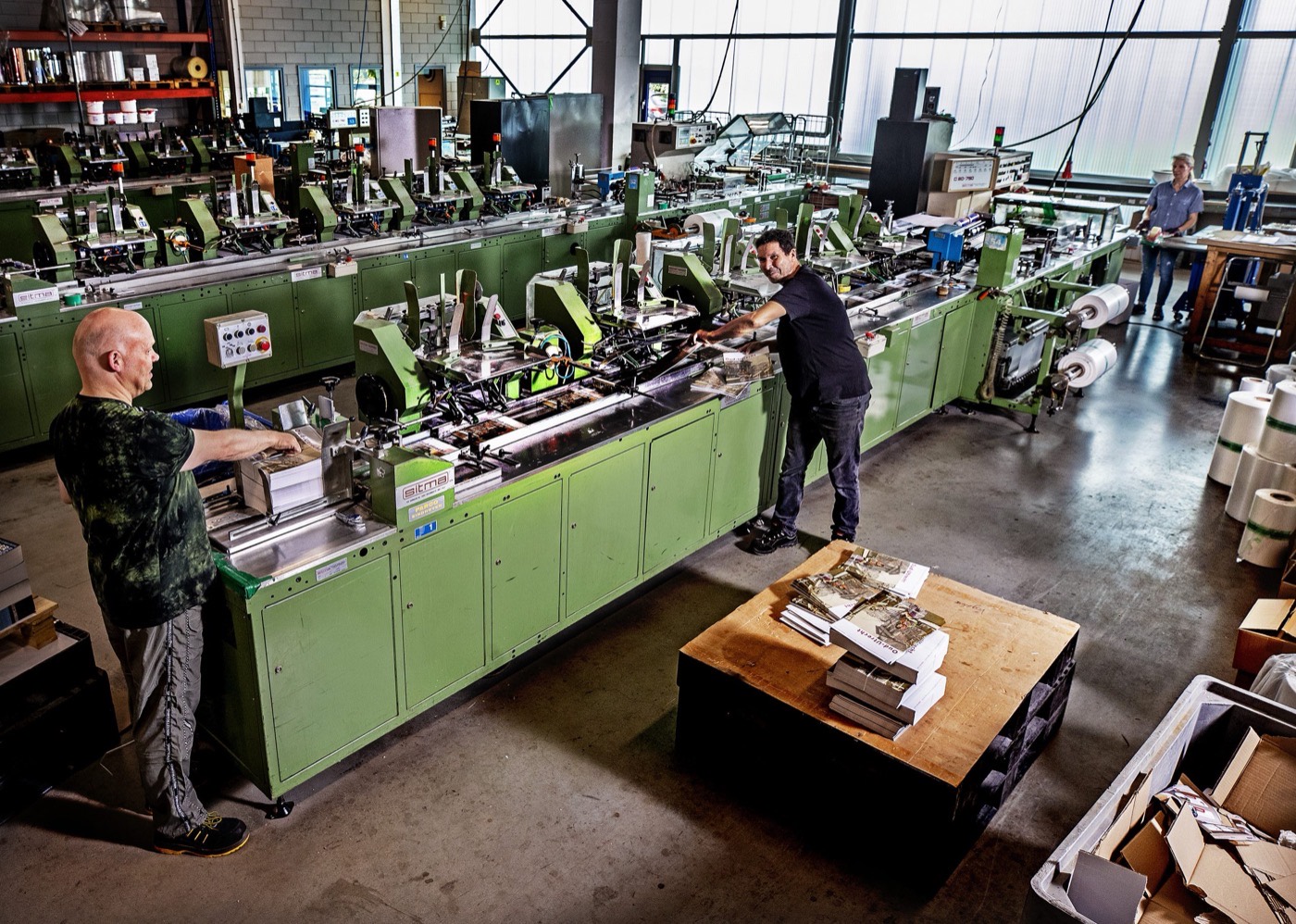 Drie medewerkers van Vogelaar aan een afwerkmachine in de productiehal.
