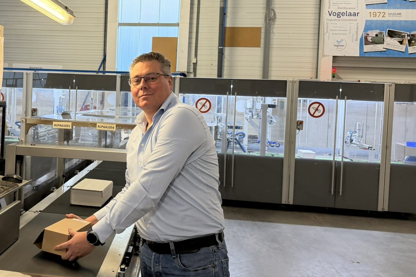 Jeroen Balke, operationeel directeur van Vogelaar, staat bij de CMC CartonWrap-inpakmachine en houdt een op maat gevouwen doos vast.